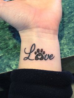 a wrist tattoo with the word love written on it