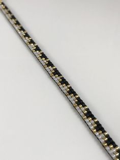 a black and gold bracelet on a white surface