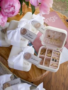 an assortment of wedding rings and jewelry sitting on top of a table next to pink flowers