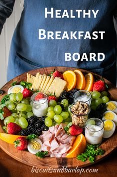 a wooden platter filled with assorted fruits and cheeses on top of a table