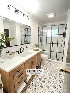 a bathroom with two sinks and a large mirror over the shower area that is decorated in black and white tile