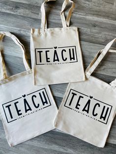 three canvas bags with the words teach written in black on them sitting on a wooden floor