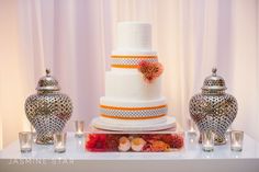 a white wedding cake sitting on top of a table next to vases and candles