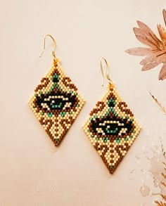 a pair of beaded earrings sitting on top of a table next to a flower