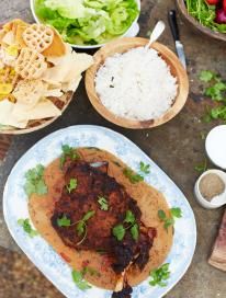 a table topped with plates and bowls filled with food next to rice, salad and meat