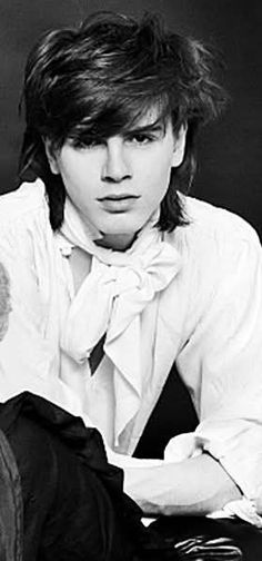 black and white photograph of a young man with long hair, wearing a bow tie