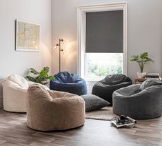 a living room filled with lots of different types of chairs and bean bags on the floor