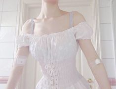 a mannequin dressed in white with gloves on her arm and hand over her shoulder