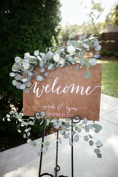 a welcome sign with greenery on it