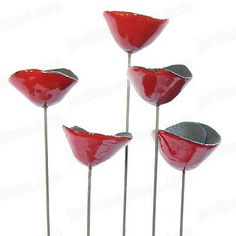 four red glass flowers sitting on top of each other with metal stems in the middle