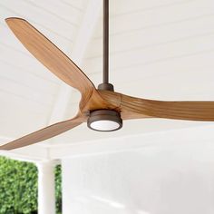 a ceiling fan with wooden blades hanging from it's center point in an outdoor room