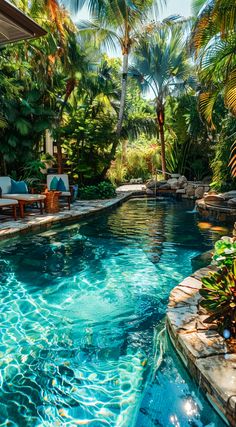 an outdoor swimming pool surrounded by palm trees and other greenery, with chaise lounges on the side