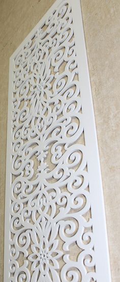 an intricately designed wall panel is shown on the floor in front of a beige background