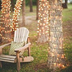 a white chair sitting next to a tree covered in lights