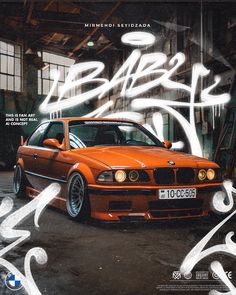 an orange car parked in a garage with graffiti on it