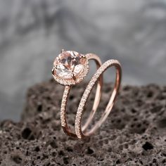 an engagement ring set with a pink morganite and diamond band on top of a rock