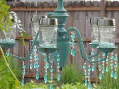 a blue chandelier with glass jars hanging from it's arms in a garden