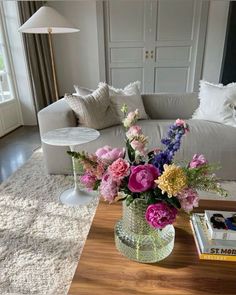 a vase filled with flowers sitting on top of a table next to a white couch