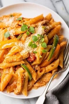 a white plate topped with pasta covered in sauce and parmesan sprinkles