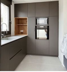 a kitchen with gray cabinets and white counter tops, along with a window in the wall