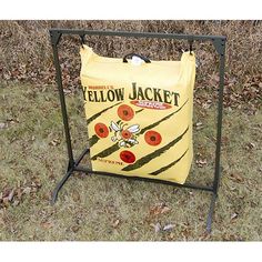 a yellow jacket bag sitting on top of a metal rack in the grass next to a bush