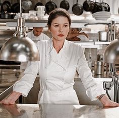 a woman standing in front of a counter with two lamps on top of her head