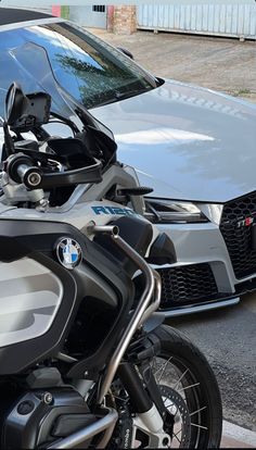 two motorcycles parked next to each other in front of a gray car and another vehicle