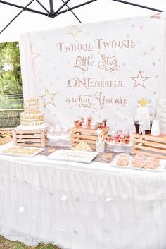 a table topped with lots of desserts under a white tent covered by a tarp