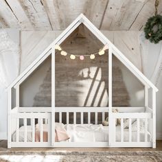 a white crib in a room with wooden walls and ceiling beams, decorated for christmas