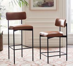 two brown leather barstools sitting next to each other in front of a window