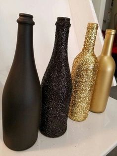 three black and gold vases sitting on top of a white counter next to each other