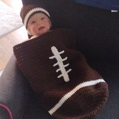 a baby wrapped in a crochet football blanket