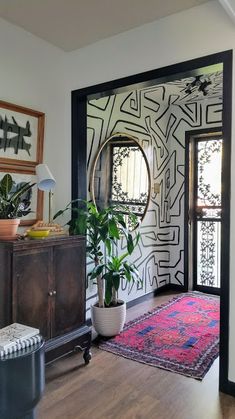 a living room with a rug, potted plant and large mirror on the wall