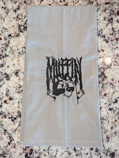 a kitchen towel with the word written on it and a cartoon character holding a knife