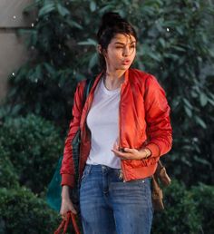 a woman walking in the rain with her hand on her hip and looking at her cell phone