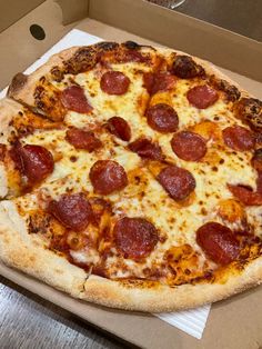 a pepperoni pizza sitting on top of a cardboard box