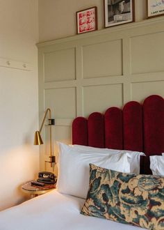 a neatly made bed with red headboard and pillows