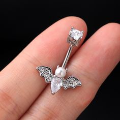 a close up of a person's hand with a ring on it and a bat shaped nose pin