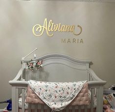 there is a baby crib with a blanket on it and a name sign above the crib