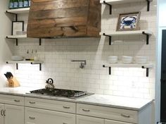 a kitchen with white cabinets and marble counter tops, open shelving above the stove