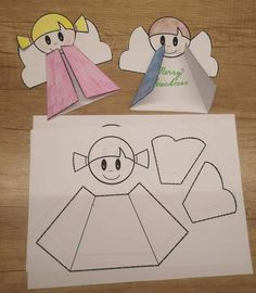 paper cut out of the shape of an angel and another piece of paper with scissors