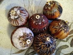 five different types of fruit sitting on a white plate with brown and black designs around them