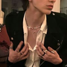 a woman wearing a white shirt and black jacket with rings on her chest, holding onto the collar of another person's neck