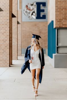 a woman in a graduation cap and gown walking down the street