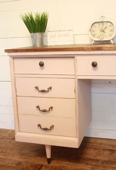 a white desk with drawers and a clock on top