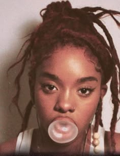 a woman with dreadlocks blowing bubbles in her mouth