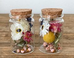 two glass jars with flowers and cork lids