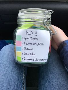 a person sitting in the back seat of a car holding a jar with notes on it