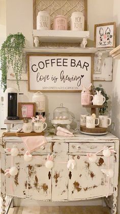 a coffee bar is decorated with pink and white decor, such as mugs on top of an old dresser