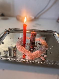 a candle that is sitting on top of a tray with some kind of thing in it